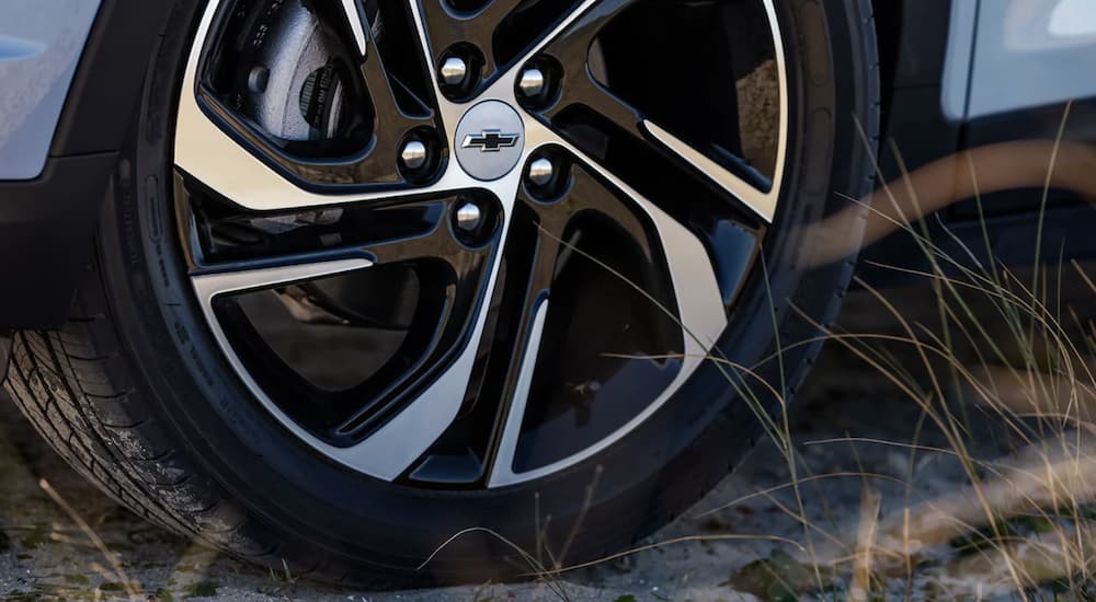 The black tire on a 2022 Chevy Bolt EV is shown parked on the sand.