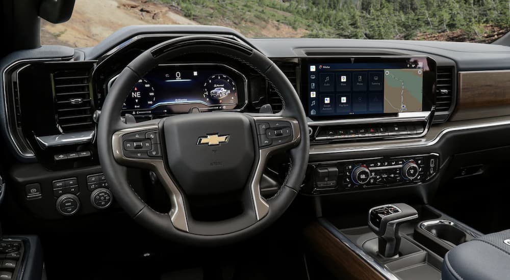The grey interior of a 2022 Chevy Silverado 1500 shows the steering wheel and infotainment screen after leaving a Chevy dealer.