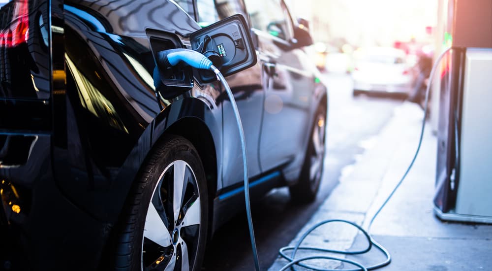 A black vehicle is shown plugged into a charging station.