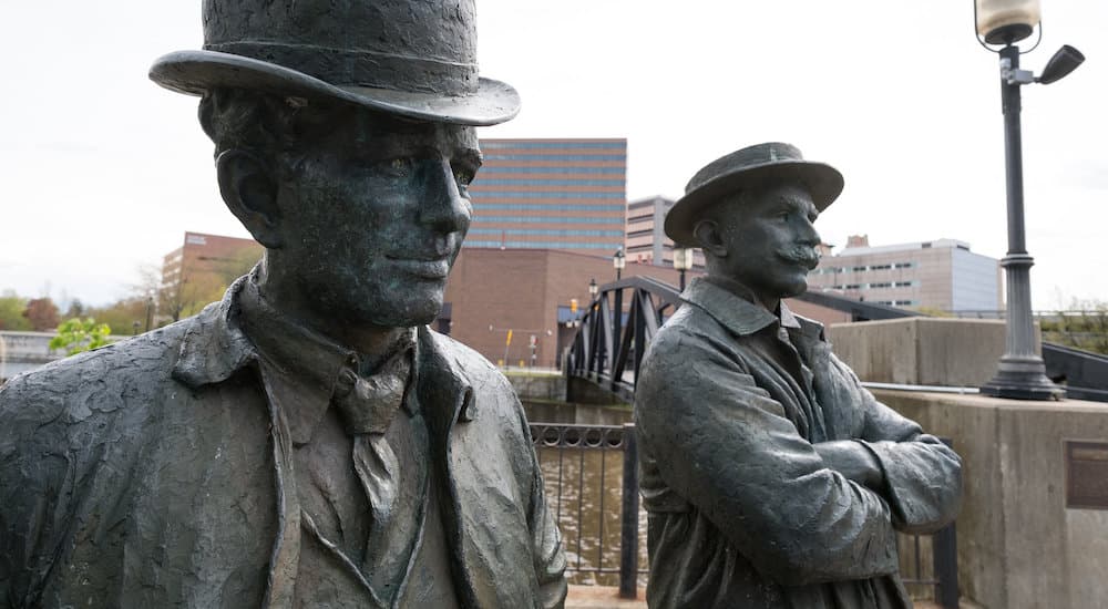 A close up shows the statues of William Durant and Josiah Dallas Dort.