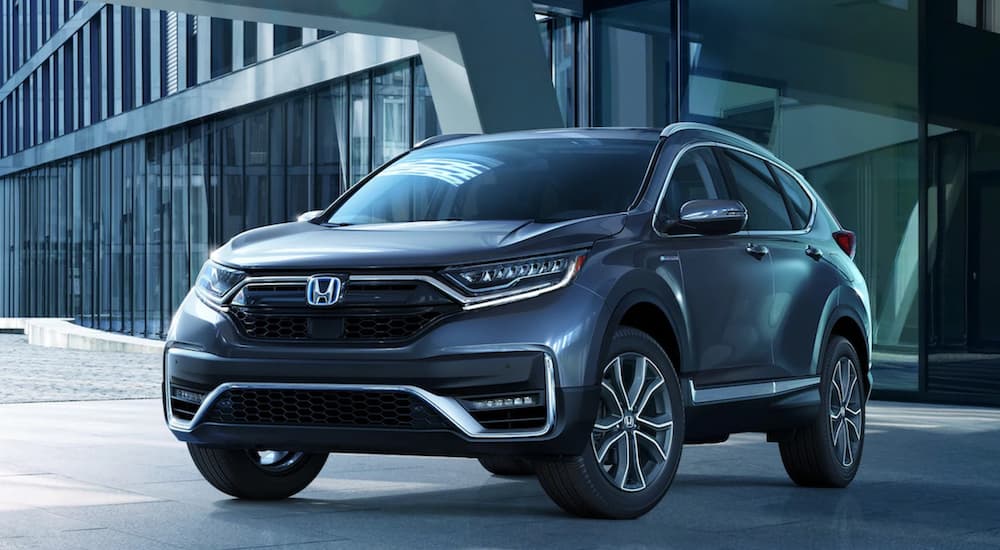 A blue 2022 Honda Cr-V Hybrid Touring is shown angled left parked at a Honda dealer.