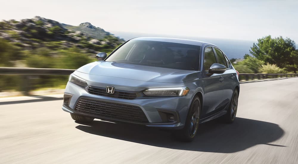 A grey 2022 Honda Civic Sedan is shown from the front driving on an open road.