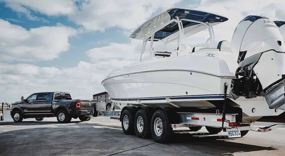 a black 2022 Ram 3500 is shown from the back as it tows a large boat.