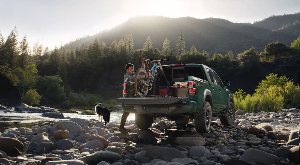 A green 2022 Nissan Frontier PRO-4X is shown parked on a rocky river bank.