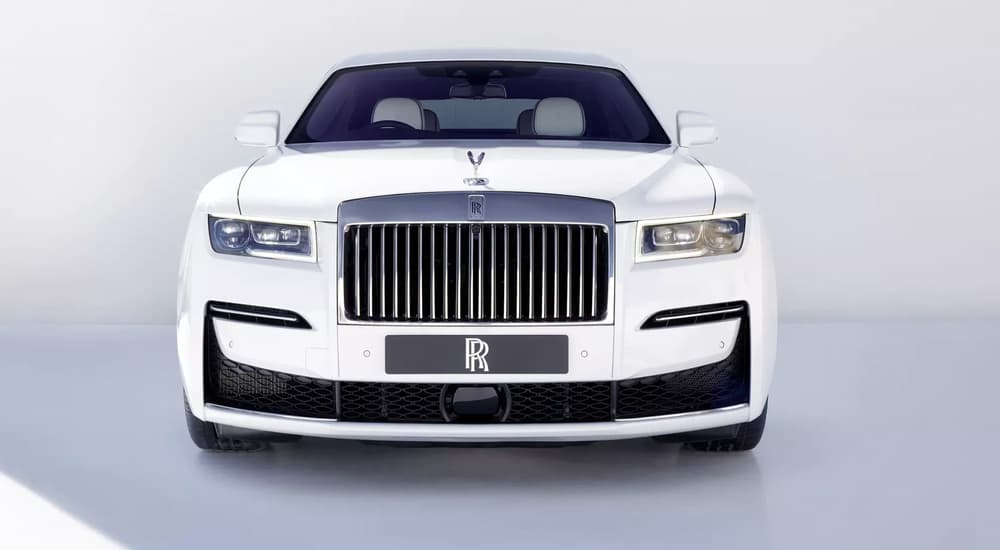 A white Rolls Royce Ghost is shown from the front on a light grey background.