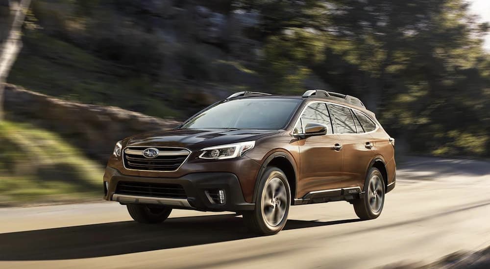 A brown 2022 Subaru Outback Touring is shown from the front driving on an open road after leaving a Subaru dealer.
