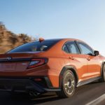 An orange 2022 Subaru WRX Limited is shown from the rear driving on an open road.