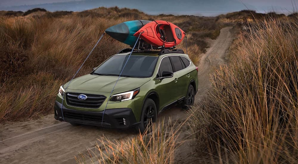 A green 2022 Subaru Outback is shown on a dirt road after leaving a Subaru dealership.