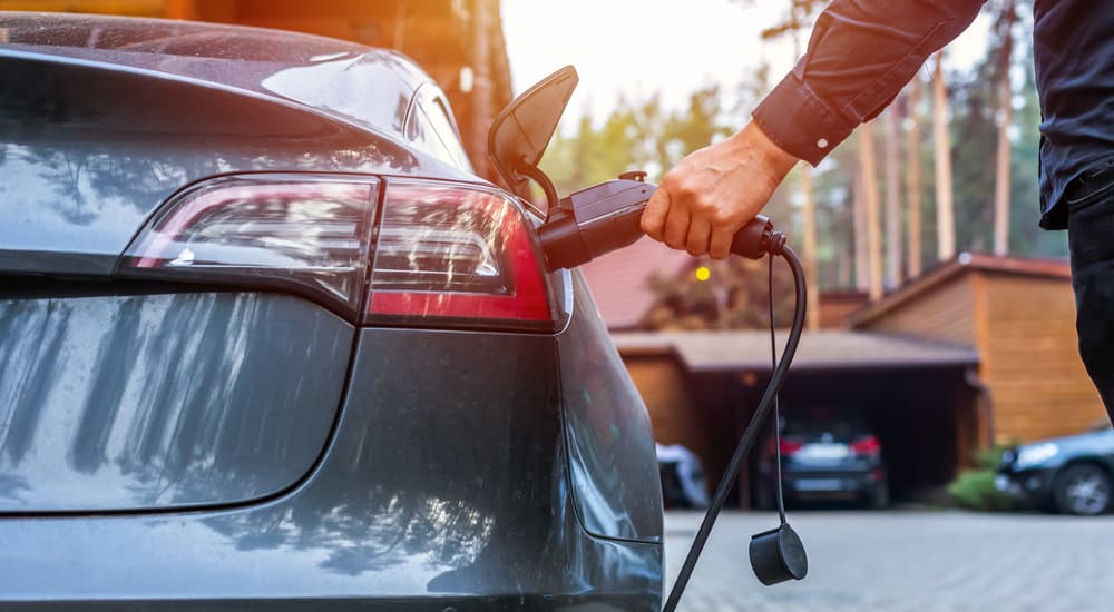 A close up of the man charging a grey Tesla.