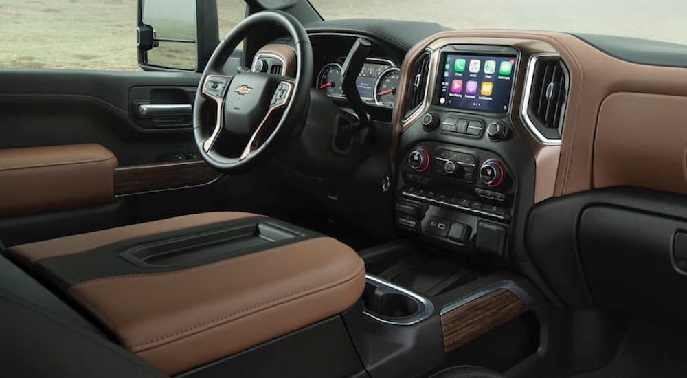 The black and tan interior of a 2020 Chevy Silverado 2500 HD shows the steering wheel and infotainment screen.