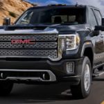 A black 2022 GMC Sierra 2500 is shown from the front driving on an open road after leaving a used GMC 2500 truck dealer.