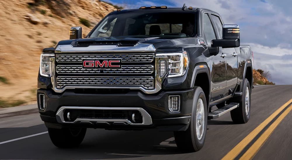 A black 2022 GMC Sierra 2500 is shown from the front driving on an open road after leaving a used GMC 2500 truck dealer.