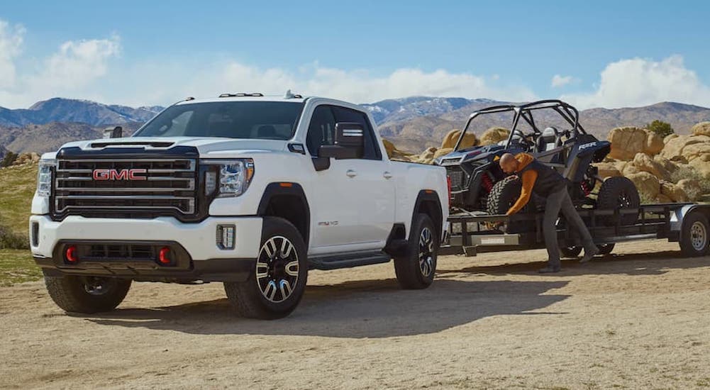 A white 2020 GMC Sierra 2500 AT4 is shown parked towing a trailer.