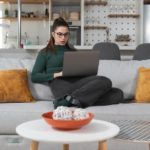 A person is shown doing used car dealership research on a laptop.