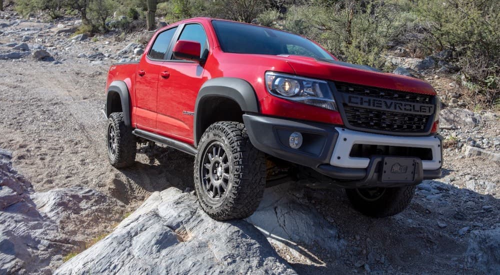 A red 2020 Chevy Colorado ZR2 Bison is shown from the front while climbing over a rock.