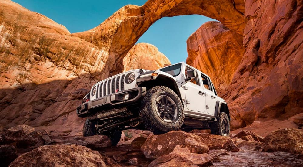 A white 2022 Jeep Wrangler Rubicon is shown driving over rocks.
