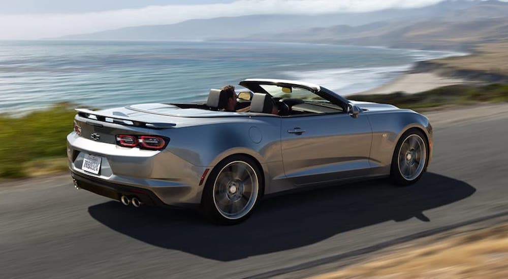 A silver 2022 Chevy Camaro is shown from the rear on a coastal road.