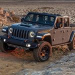 A 2022 Jeep Gladiator Mojave is shown from the front at an angle while crawling through rocks during a 2022 Jeep Gladiator vs 2022 Chevy Colorado comparison.