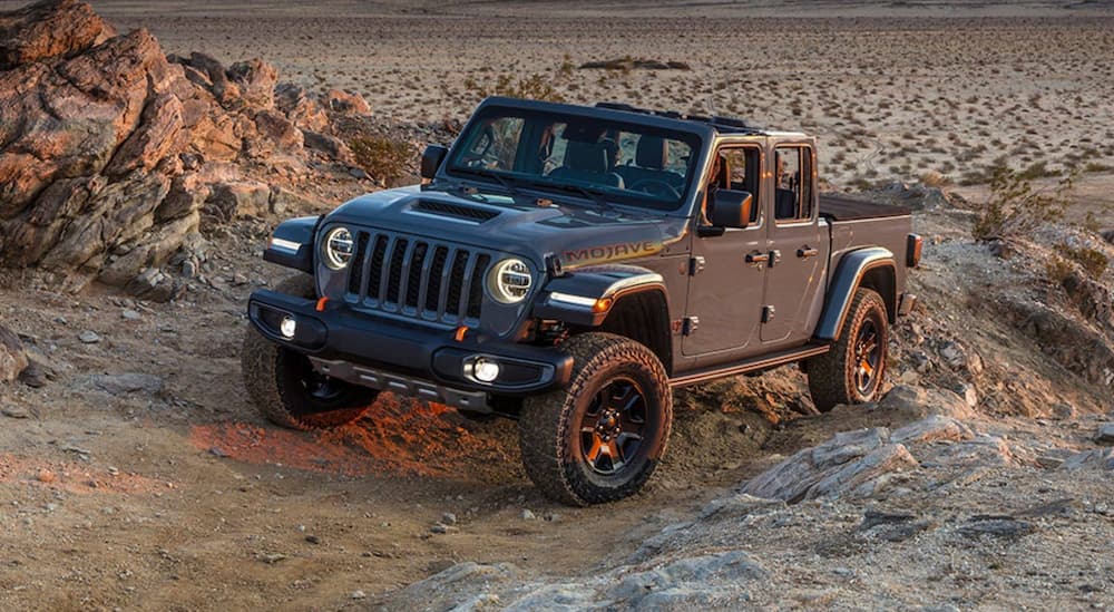 A grey 2022 Jeep Gladiator Mojave is shown from the front at an angle while driving through the desert after leaving a Fountain Jeep dealer.