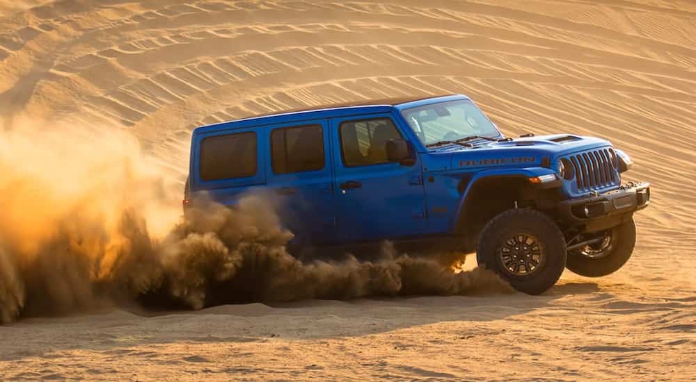 A blue 2022 Jeep Wrangler Rubicon 392 is shown from the side while it drives through the desert.