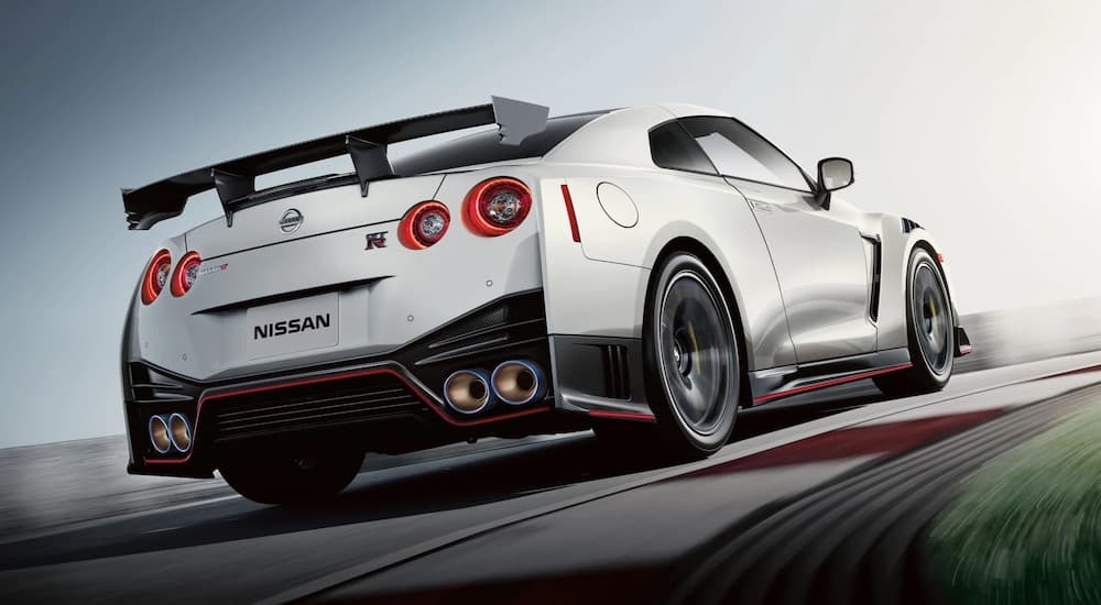 A white 2021 Nissan GT-R Nismo is shown from the rear on a racetrack after leaving a Nissan Dealer.