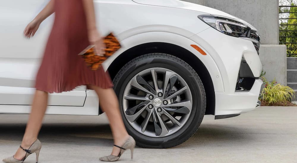A close up of a person is shown walking past a white 2022 Buick Encore GX.