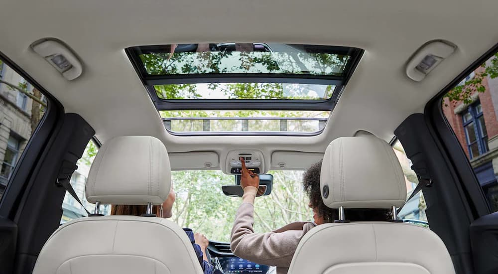 A person is shown opening the sunroof in a 2022 Buick Encore GX.