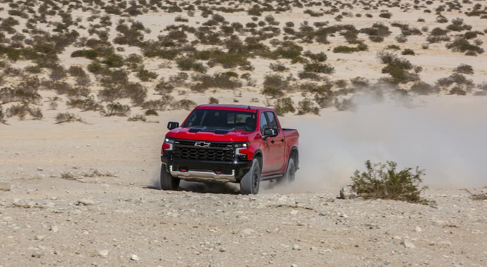A red 2022 Chevy Silverado ZR2 is shown from the front at an angle while speeding through the desert.