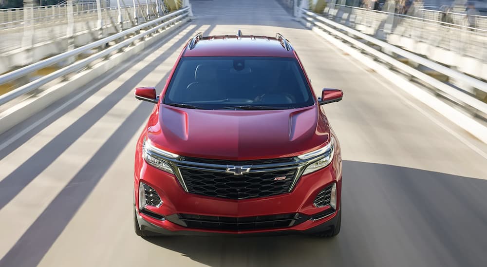 A red 2022 Chevy Equinox RS is shown from the front driving on an open road during a 2022 Chevy Equinox vs 2022 Jeep Cherokee comparison.