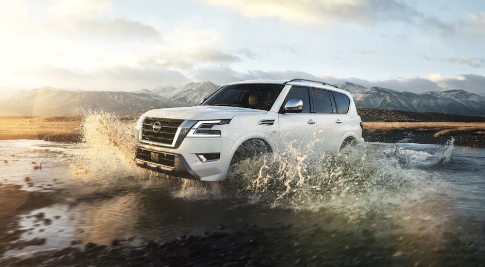 A white 2022 Nissan Armada is shown from the side driving through a river.
