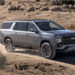 A silver 2022 Chevy Suburban Z71 is shown from the front driving on a dirt road during a 2022 Chevy Suburban vs 2022 Nissan Armada comparison.