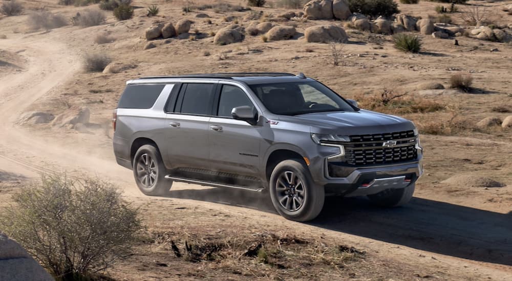 A silver 2022 Chevy Suburban Z71 is shown from the front driving on a dirt road during a 2022 Chevy Suburban vs 2022 Nissan Armada comparison.
