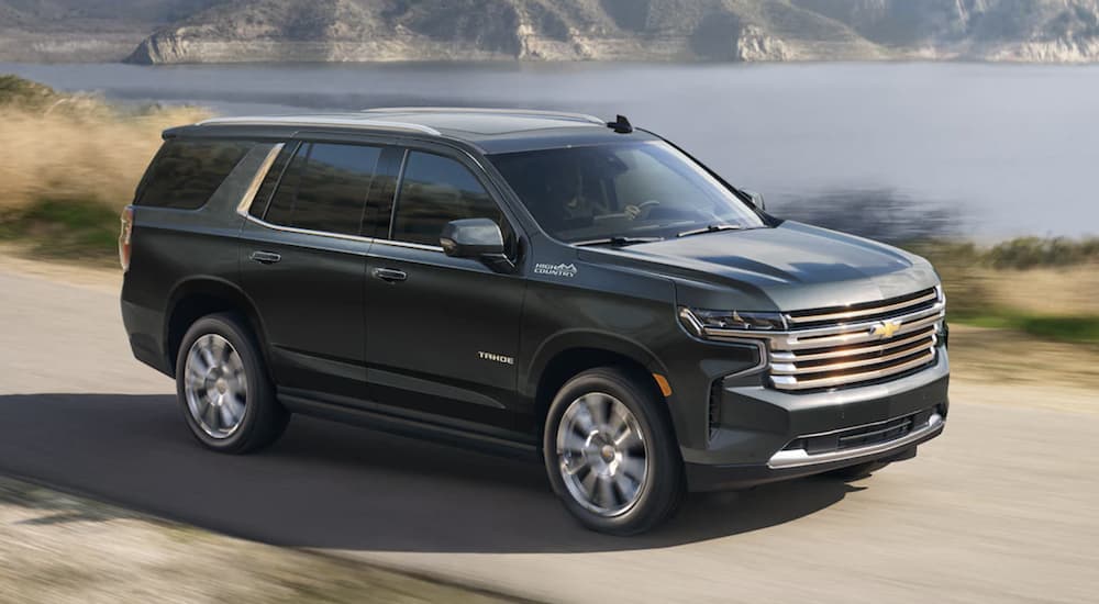 A black 2022 Chevy Tahoe High Country is shown from the side driving on an open road.