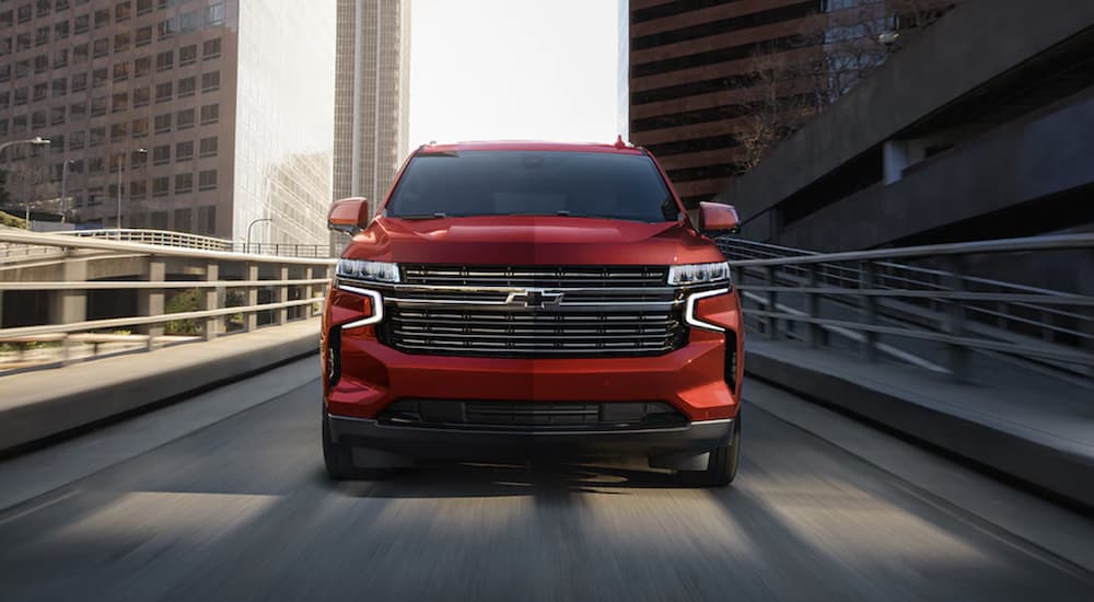 A red 2022 Chevy Tahoe is shown from the front driving through a city.