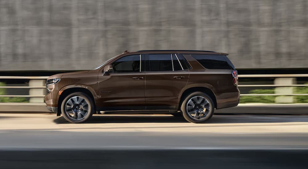 A gold 2022 Chevy Tahoe is shown from the side driving on an open road.