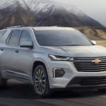 A silver 2022 Chevy Traverse is shown from the front driving on an open road.