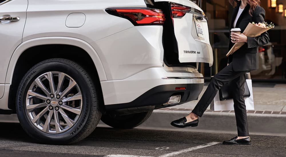 A person is shown opening the lift gate of a white 2022 Chevy Traverse with their foot.