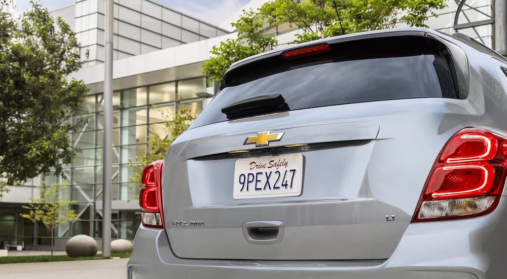 The rear liftgate of a silver 2022 Chevy Trax is shown in the city.