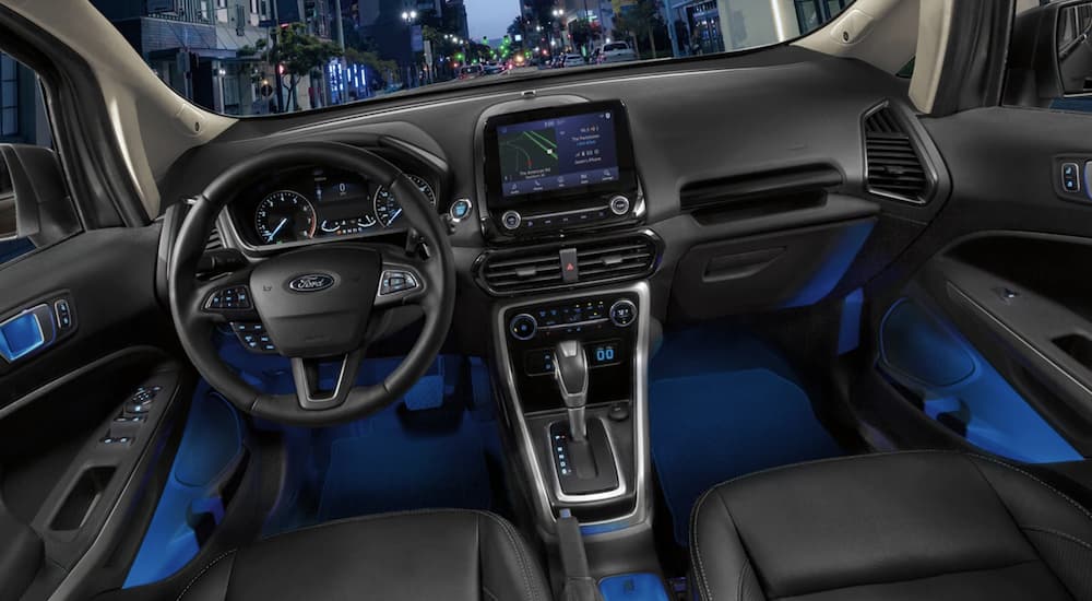 The black interior of a 2022 Ford EcoSport shows the steering wheel and infotainment screen.