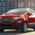 A red 2022 Ford EcoSport is shown from the front driving through a city.