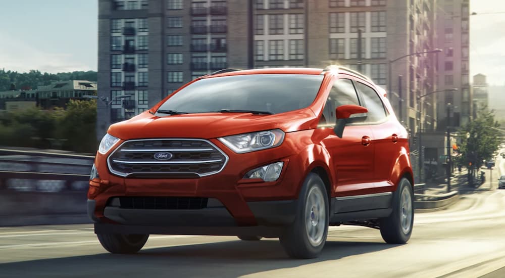 A red 2022 Ford EcoSport is shown from the front driving through a city.