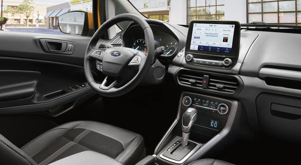 The black interior of a 2022 Ford EcoSport shows the steering wheel and infotainment screen.