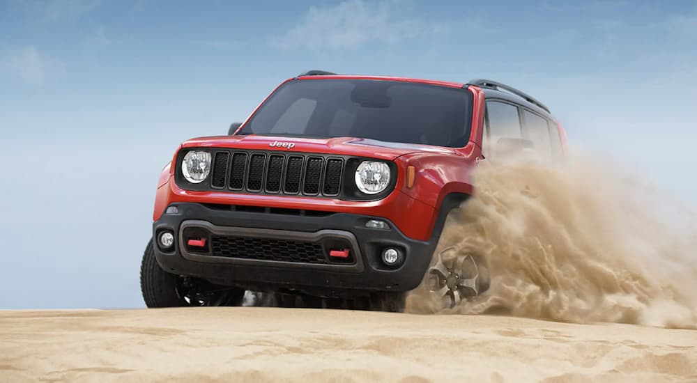 A red 2022 Jeep Renegade is shown off-roading in a desert.