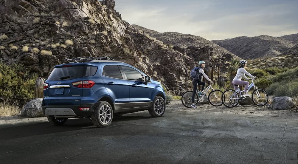 A blue 2022 Ford EcoSport is shown from the rear parked in front of a mountain during a 2022 Ford EcoSport vs 2022 Jeep Renegade comparison.