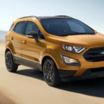 A gold 2022 Ford EcoSport is shown from the front driving on an open road.