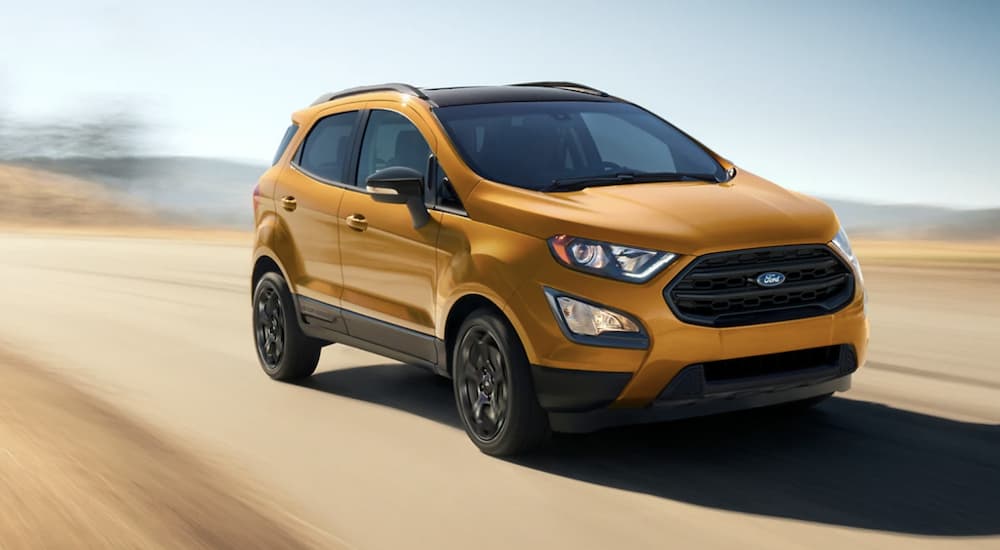 A gold 2022 Ford EcoSport is shown from the front driving on an open road.