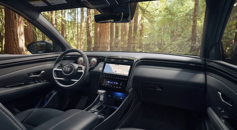 The black interior of a 2022 Hyundai Santa Cruz shows the steering wheel and infotainment screen.