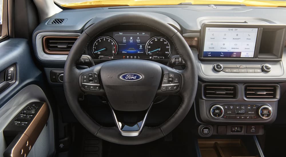 The black interior of a 2022 Ford Maverick shows the steering wheel and infotainment screen.