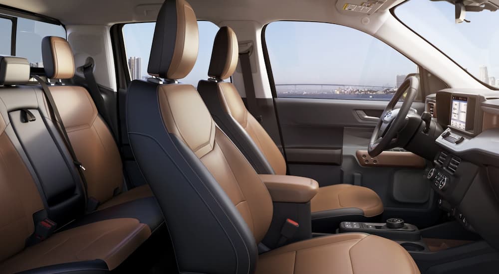 The black and brown interior of a 2022 Ford Maverick shows two rows of seating during a 2022 Ford Maverick vs 2022 Hyundai Santa Cruz comparison.