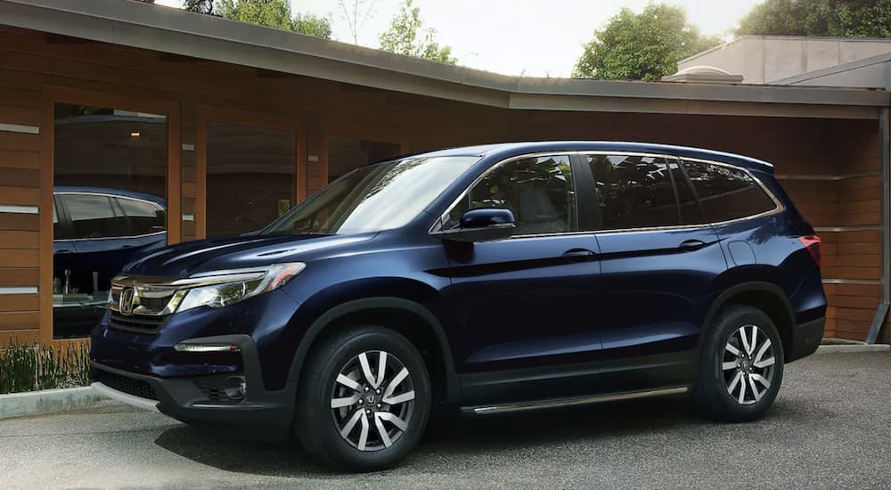A blue 2022 Honda Pilot EX-L is shown from the side parked in front of a house.